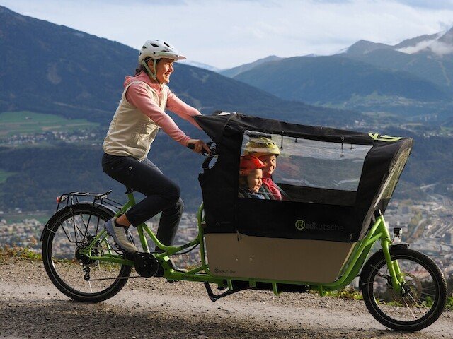 Mother and childeren drive elektrical cargo bike in the mountains