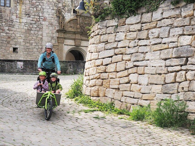 Family drives down steap hill on their elektrical cargo bike from Radkutsche