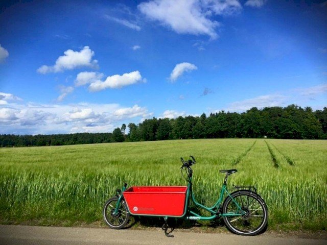 Green e cargo bike from Radkutsche stands with red wanne in the sun