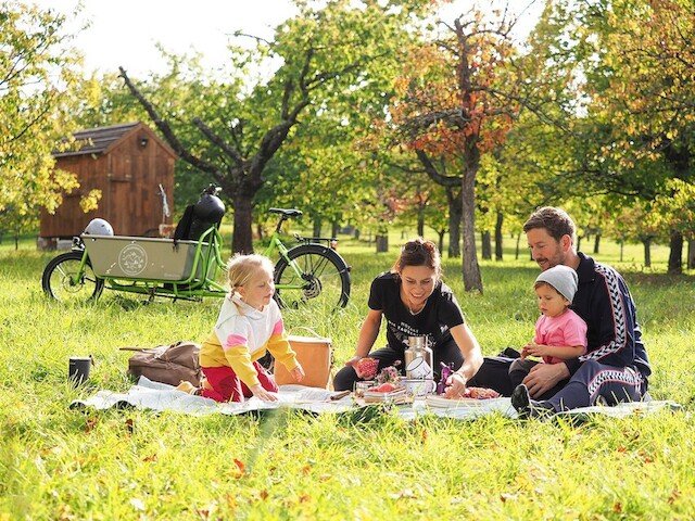 A family enjoys the sun during a picnic with their e-cargo bike from Radkutsche