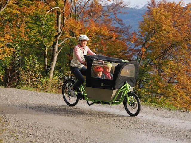 Mother riding her cargo bike on a gravel road in the forest