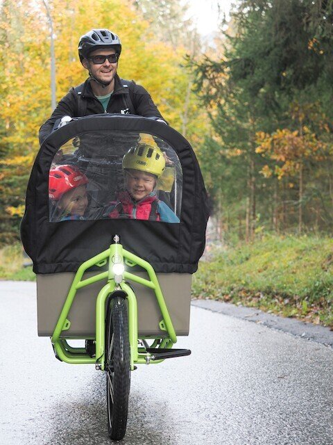 Father riding his elektrical family cargo bike in the forest