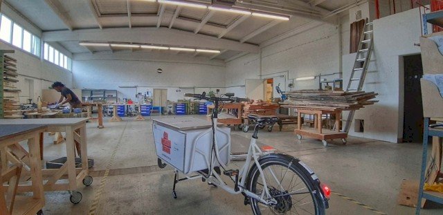 Woodworker parks cargo bike in workshop before driving to his customer
