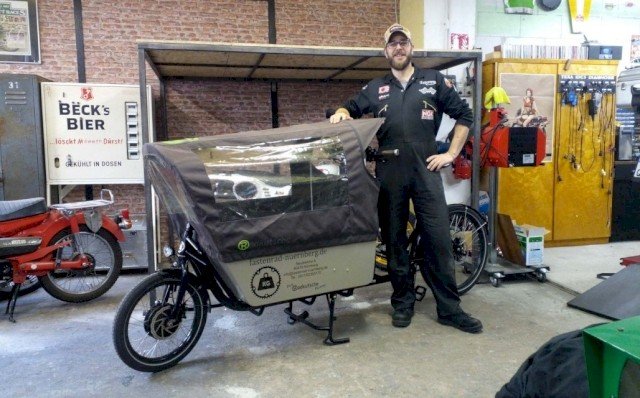 Kraftsman shows his cargo bike from Radkutsche while standing proudly next to it in his workshop