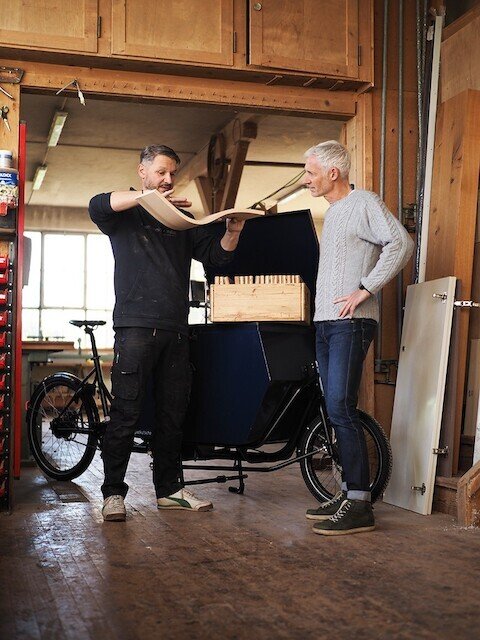 Woodworker explains a customer next to his cargo bike how wood is bend