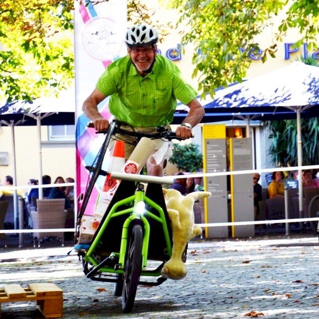 Person smiling while driving a fully packed cargo bike from Radkutsche in town