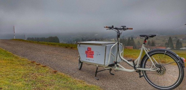 e cargo bike in the fog on a gravel road in the mountains