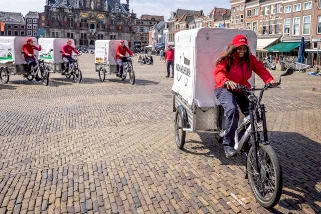 A team of garbage collectors drives on their three-wheeled cargo bikes, which they uses to collect rubbish from shops