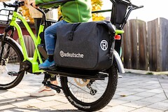 A grey Vaude bike bag with reflectors and logo print hangs on a green cargo bike from Radkutsche GmbH.