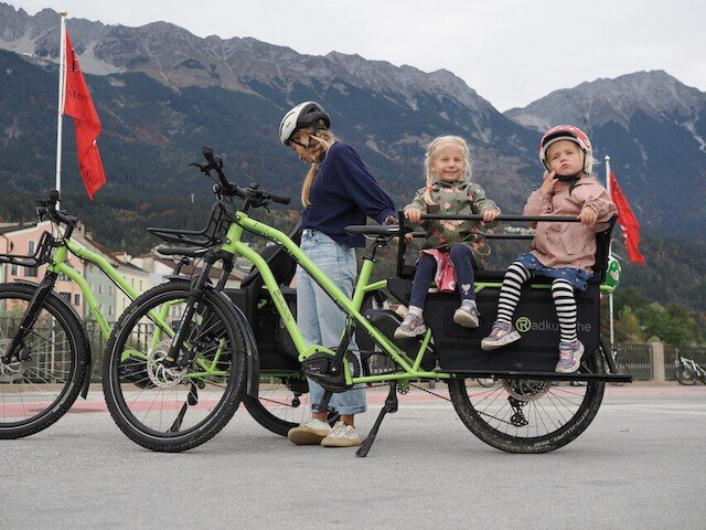 Two childeren patiently await until there mother start driving their cargo bike from Radkutsche