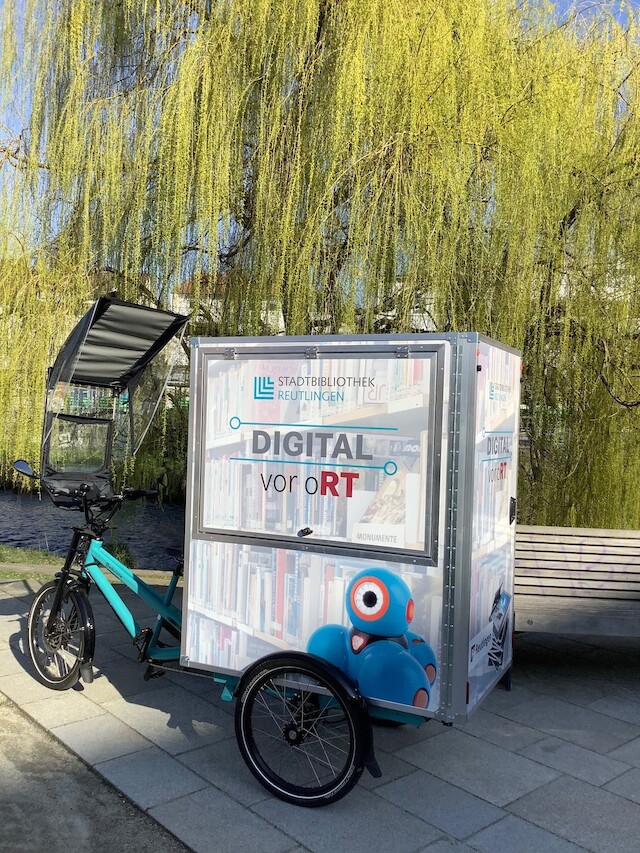 Ein hellblaues Lastenrad mit 3 Rädern ist mit einer Muskebox auf dem Hinteren teil zu sehen, womit den digitalen Wandel in Reutlingen unterstützt würd.