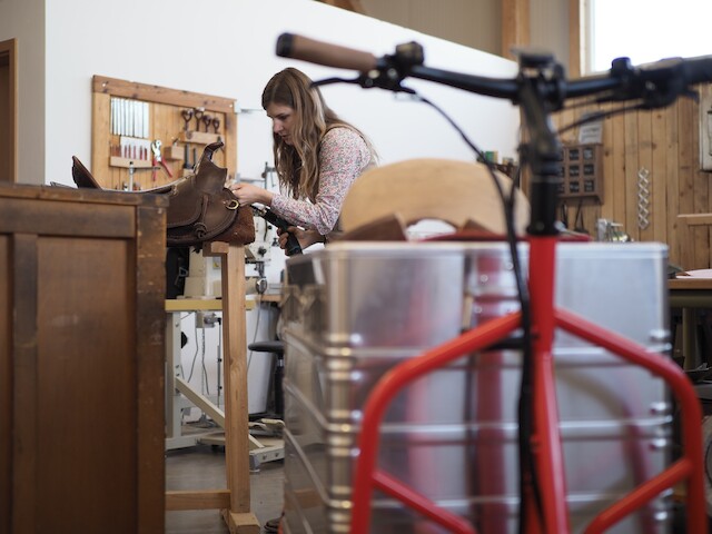 Eine Sattelmacherin arbeitet an ihrem nächsten Stück, nachdem sie mit ihrem roten Lastenrad Rapid von Radkutsche neue Materialien abgeholt hat.