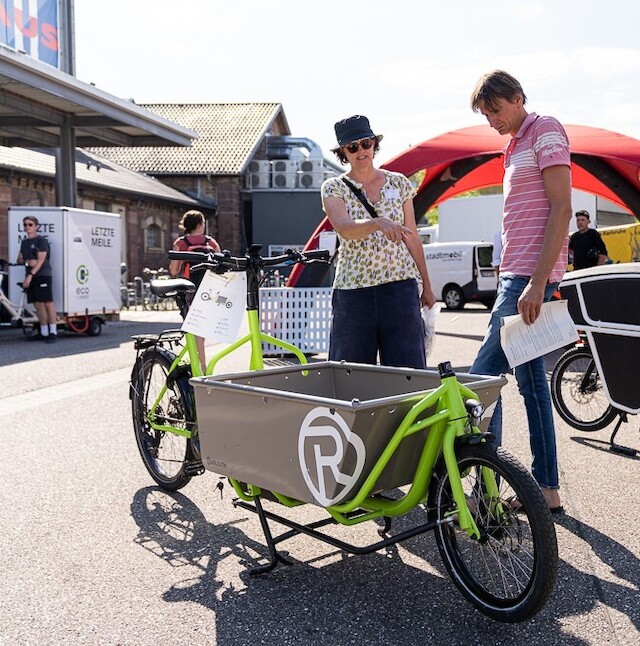 Ein Verkäufer erklärt einem potenziellen Kunden die Details, während er neben einem Lastenrad Rapid von Radkutsche steht.